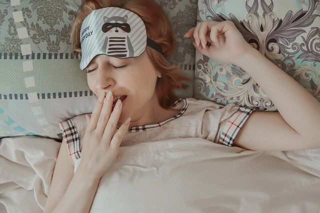 Kobieta leży w łóżku i ziewa